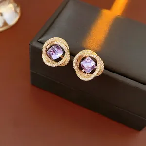 Square purple zircon earrings in gold spiral setting on a black luxury jewelry box