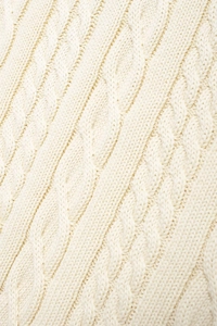 Macro shot of cream knit fabric featuring classic cable stitch pattern and soft wool texture