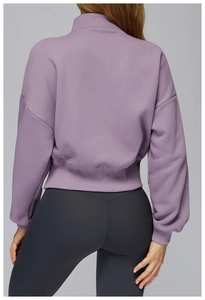 Detail view of ribbed hem on mauve stand-collar sweatshirt and gray yoga leggings