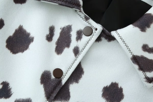 Détail de veste imprimé vache avec boutons-pression en métal et coutures en zigzag