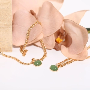 Macro detail of natural green aventurine stone pendant on 18K gold plated Figaro chain