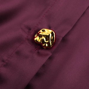 Close-up of artistic gold metal button on a fuchsia satin silk commuter shirt for women