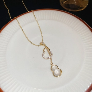 Gros plan détaillé du pendentif gourde doré orné de petites pierres en zircone