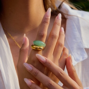 Dettaglio di una modella che indossa un anello in avventurina verde e una fascia dorata