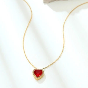 Macro view of gold plated heart necklace with red gemstone and cubic zirconia halo
