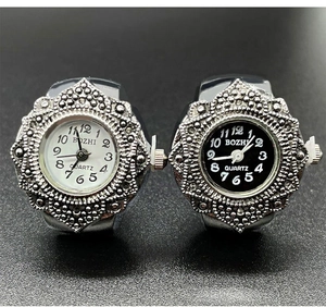 Close-up of quartz ring watches with ornate silver metal cases in black and white dials
