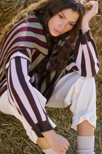 Outdoor close-up showing thick knit texture and retro color-block stripes on a loose sweater
