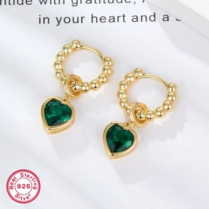 Macro view of S925 sterling silver gold beaded earrings with emerald green heart charms
