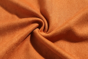 Macro shot of dark orange suede fabric with fine texture for autumn men jacket