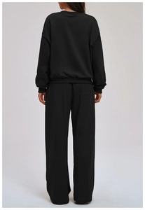 Detail of minimalist black sweatshirt and wide-leg jogger pants with ribbed cuffs