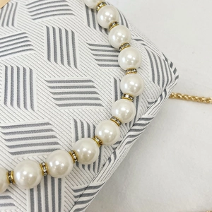 Detail of shell bag featuring pearl handle with rhinestone accents and geometric texture