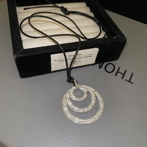 Detail of multi-layer sparkling crystal concentric circle pendant on a black cord