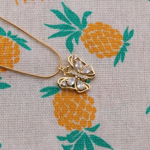 Macro shot of gold butterfly pendant with sparkling clear crystals on fabric