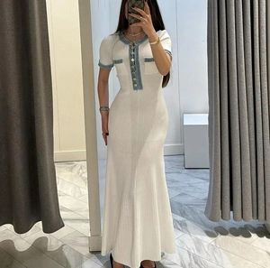 Detail of white knit dress featuring blue contrast trim and metallic button accents