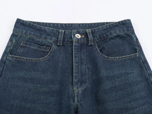 Gros plan de la taille d'un jean bleu foncé avec bouton argenté et surpiqûres