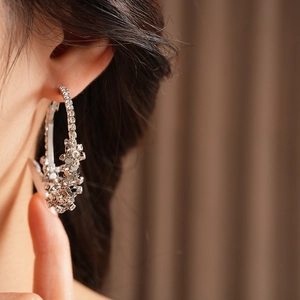 Gros plan de grandes créoles argentées avec strass étincelants sur l'oreille du mannequin