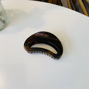 Close-up of semi-circle tortoiseshell hair claw clip with glossy brown resin texture