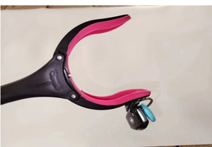 Detail of pink rubber non-slip claw of the grabber tool holding a car key firmly