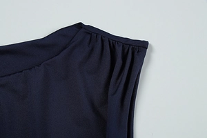 Detail shot of the navy blue dress showing gathered shoulder pleats and smooth fabric texture