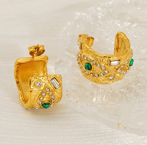 Détail macro de boucles d'oreilles dorées texturées avec malachite et cristaux brillants