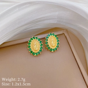 Macro shot of gold Virgin Mary earrings with emerald green gemstones and 18K gold texture