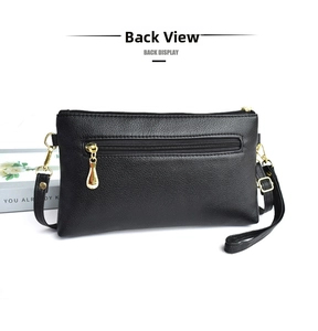 Macro view of black litchi pattern leather clutch with gold zipper back pocket