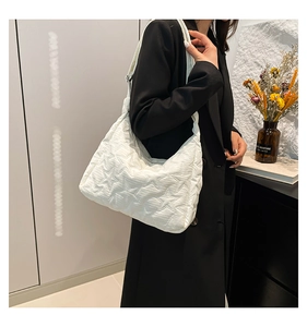 Close-up of white quilted shoulder bag featuring star embroidery and soft cloud texture
