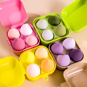 Macro view of four gradient makeup sponges sets in colorful storage boxes on table