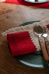 Close-up of woven Christmas placemat with red and white stripes and tassel details