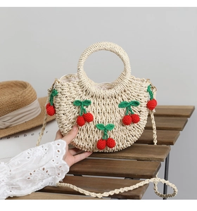 Detailansicht der handgefertigten Strohtasche mit Kirsch-Deko und abnehmbarem Gurt