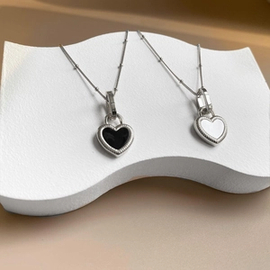 Detail of double-sided black and white heart pendant on a silver titanium necklace