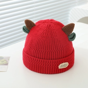 Detail of red knit hat featuring brown horns, green ears and a HOW label tag