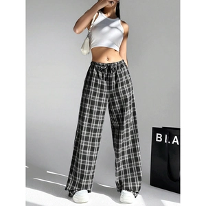 Detailed view of high-waisted black and white plaid wide-leg trousers with drawstring