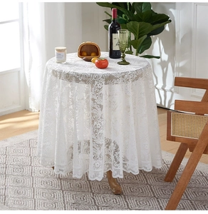 Detailed view of white openwork lace tablecloth with elegant ruffled edges on a round table