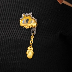 Macro shot of surrealist eye brooch with gold metal lashes and hanging chain on black knit
