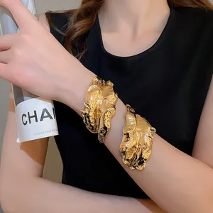 Detailed view of the golden liquid metal textured leaf cuff bracelet on a female model
