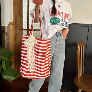 Detail of red and white striped canvas tote bag with butterfly embroidery and lace detail