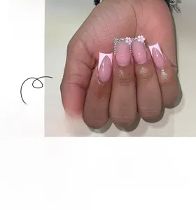 Close-up of pink French press-on nails featuring 3D white flowers and sparkling rhinestones