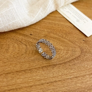 Close-up of a silver hollow floral ring with zircon on a natural wooden background