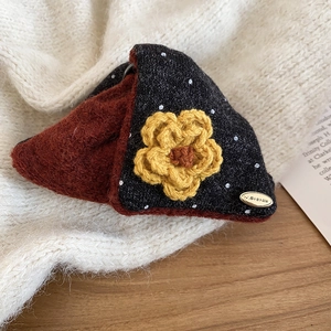 Detail of a triangle knitted coin purse with polka dots and a yellow crochet flower