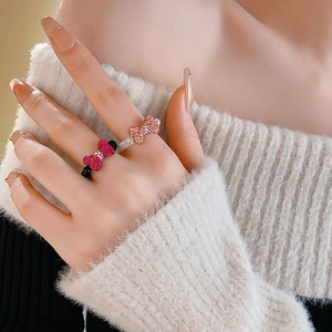 Close-up of sparkling rhinestone bow rings in rose pink and champagne on model's hand