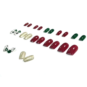 Christmas themed press-on nails with cartoon trees and glitter in red and green colors
