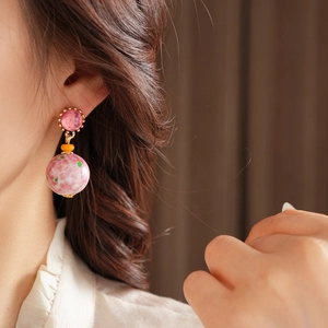 Vue détaillée de boucles d'oreilles rondes en céramique rose de style vintage sur mannequin