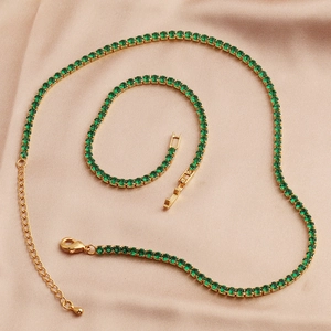 Detail of emerald green zircon tennis necklace and bracelet on beige silk fabric