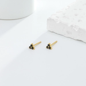 Macro shot of minimalist gold S925 silver stud earrings with black cluster gems