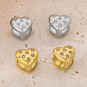 Detail of heart huggie earrings with star engravings and cubic zirconia on stone background