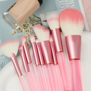 9-piece makeup brush set with pink gradient bristles and transparent handles on a tray