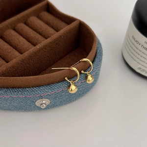 Chic 925 silver golden hoop earrings with small spherical charms on a jewelry box edge