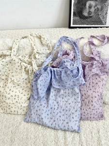 Floral print tote bag with ruffle trim available in cream, blue, and purple colors