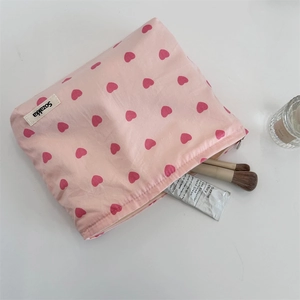 Detail of pink heart canvas makeup bag with zipper closure and feminine styling